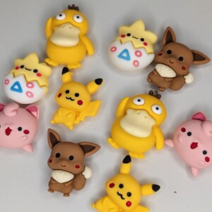 Puede incluir: Una colecci&oacute;n de figuras de personajes de dibujos animados coloridos. Las figuras incluyen Pikachu amarillo, Eevee marr&oacute;n, Jigglypuff rosa y Psyduck amarillo. Algunos est&aacute;n en huevos. Las figuras probablemente sean de pl&aacute;stico o resina.