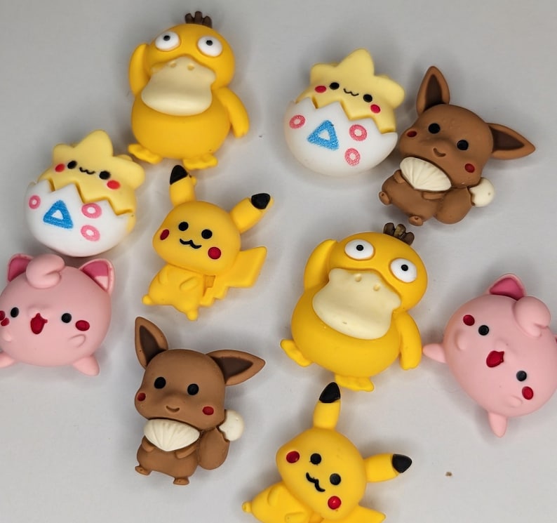 Puede incluir: Una colecci&oacute;n de figuras de personajes de dibujos animados coloridos. Las figuras incluyen Pikachu amarillo, Eevee marr&oacute;n, Jigglypuff rosa y Psyduck amarillo. Algunos est&aacute;n en huevos. Las figuras probablemente sean de pl&aacute;stico o resina.