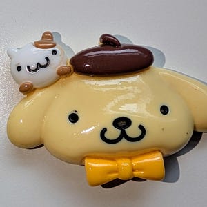 May include: A yellow and brown cartoon dog figurine wearing a brown hat and a yellow bow tie. The dog has a small white cat figurine on its back.
