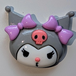 May include: A gray and white character with pink bows and a pink skull on its head. The character has large eyes and a small pink nose.