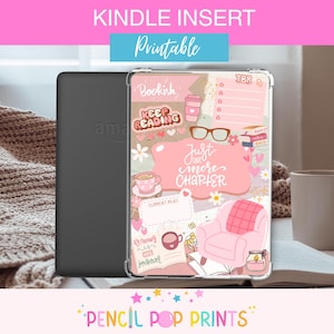 May include: A Kindle e-reader with a clear case featuring a pink and beige design with the words "Bookish", "Keep Reading", and "Just One More Chapter". The case has a cozy reading theme with a teacup, glasses, and a small armchair.