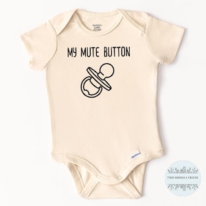 May include: Cream-colored baby onesie with the text "MY MUTE BUTTON" above a black and white illustration of a pacifier. The onesie has short sleeves and snap closures.