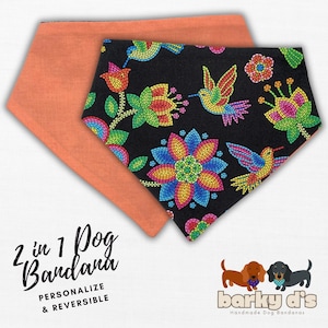 May include: A reversible dog bandana with a black background and colorful floral and hummingbird pattern on one side and a solid coral color on the other side. The bandana is labeled "2 in 1 Dog Bandana, Personalize & Reversible" and "barky di's Handmade Dog Bandanas".