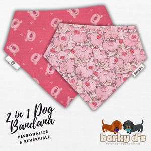 May include: Two pink dog bandanas with a pig print. One bandana has a pink background with white pigs and the other has a white background with pink pigs. The bandanas are reversible and say "2 in 1 Dog Bandana" and "Barky D's Handmade Dog Bandanas".