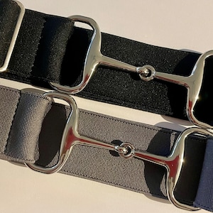 May include: Two elastic belts with silver snaffle buckles. One belt is black and the other is gray.
