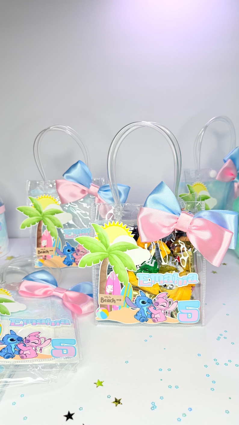 May include: Clear plastic gift bags with blue and pink bows. Each bag features a palm tree, sun, and cartoon characters. The bags have the name "Emahra" and the number "5" printed on them. The bags are filled with treats.