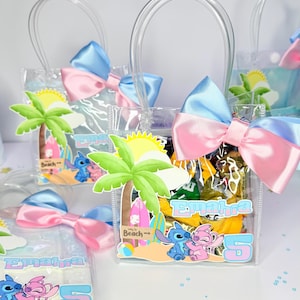May include: Clear plastic favor bags with blue and pink bows. Each bag features a beach-themed graphic with palm trees, Stitch and Angel characters, and the name "Emahra" with the number "5".