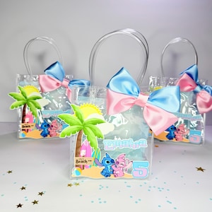 May include: Three clear plastic favor bags with clear handles, each adorned with a blue and pink bow. The bags feature a beach scene with cartoon characters and the name "Emahra" and the number "5".