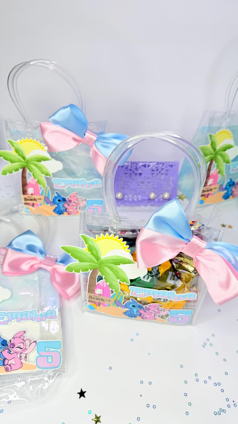 May include: Clear plastic favor bags with blue and pink bows, filled with treats. Each bag features a beach-themed graphic with a palm tree, sun, and cartoon characters. The bags have clear handles and the name "Emahra" is printed on them.