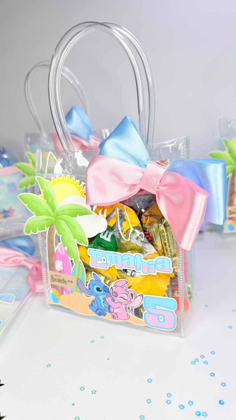 May include: Clear plastic gift bag filled with candy, featuring a beach-themed design with palm trees, surfboards, and the characters Stitch and Angel. The bag is adorned with a pink and blue bow.