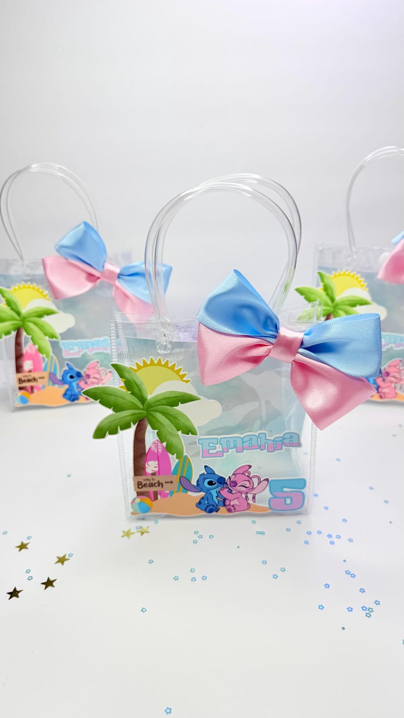 May include: Clear plastic favor bags with blue and pink bows. Each bag features a beach-themed graphic with cartoon characters and the name "Emahia" and the number "5". Palm trees and a sun are also visible.