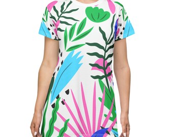 Può includere: Un abito t-shirt bianco con una stampa tropicale colorata con foglie rosa, blu e verdi.