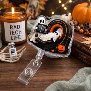May include: A clear acrylic badge reel featuring a cartoon ghost holding an X-ray film and another ghost lying on an MRI machine. The design includes a small orange jack-o'-lantern, a black bat, and the text "RADIOLOGY" on the machine.