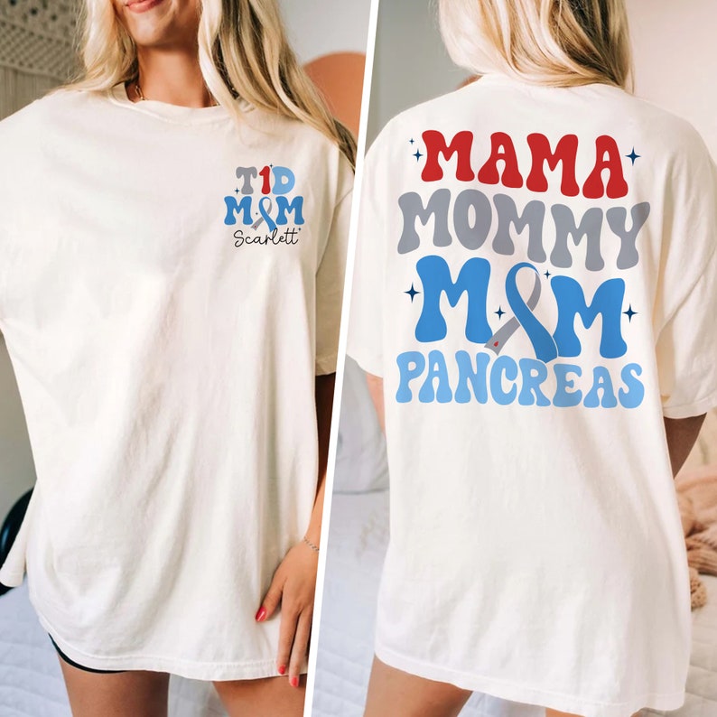 Pu&ograve; includere: Maglietta bianca con un design a nastro blu e grigio. La parte anteriore della maglietta dice "T1D M&M Scarlett". La parte posteriore della maglietta dice "Mama Mommy M&M Pancreas".