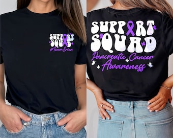 May include: Black t-shirt with a purple ribbon and the text "Support Squad" and "#Team Erica" on the front. The back of the shirt has the text "Support Squad" in a retro font with a purple ribbon and butterflies. Below the text is "Pancreatic Cancer Awareness" with butterflies.