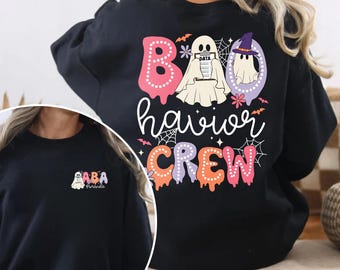 May include: Black sweatshirt with a colorful Halloween-themed design. The design includes the words "BOO havior CREW" with ghost and spiderweb graphics. A smaller version of the design is on the front of the sweatshirt, with the text "ABA Miranda".