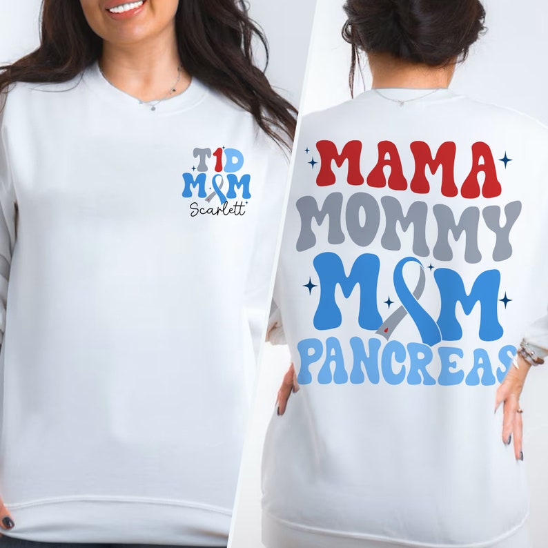 Pu&ograve; includere: Felpa bianca con un design a nastro blu e grigio. La parte anteriore della felpa dice "T1D M&M Scarlett". La parte posteriore della felpa dice "Mama Mommy M&M Pancreas".