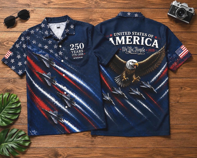 Puede incluir: Una camisa azul marino con botones y un dise&ntilde;o patri&oacute;tico. La camisa presenta estrellas blancas sobre un fondo azul, aviones y rayas rojas y blancas. La parte trasera de la camisa muestra un &aacute;guila, la bandera estadounidense y el texto "United States of America".