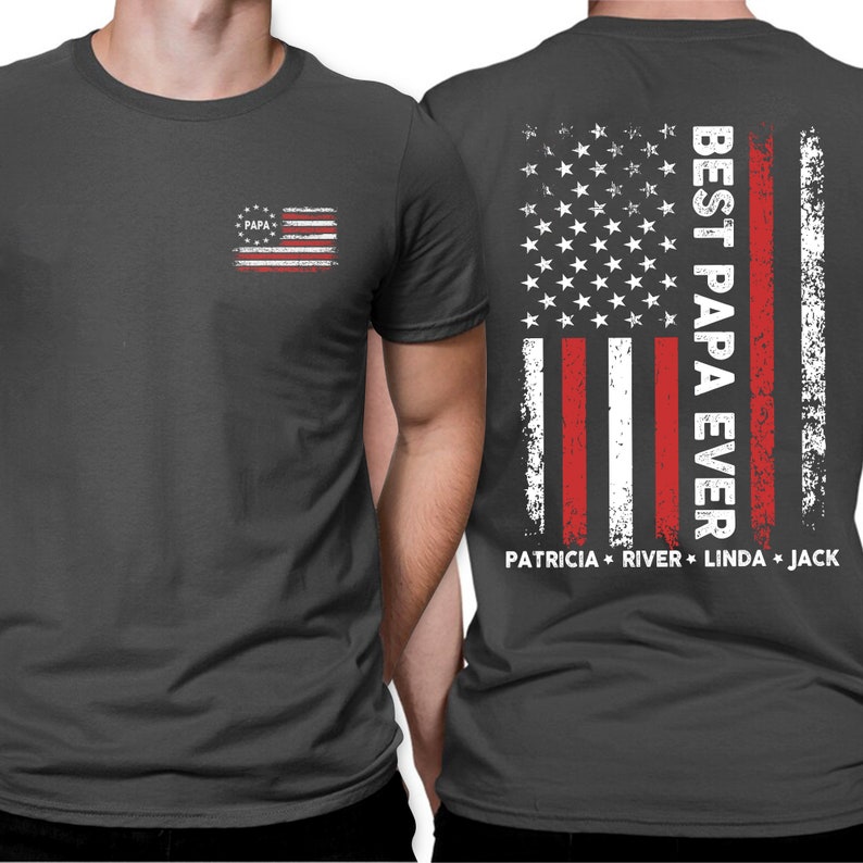 Puede incluir: Una camiseta gris oscuro con un dise&ntilde;o de bandera estadounidense desgastado en la espalda. La bandera tiene las palabras "Best Papa Ever" y los nombres "Patricia, River, Linda, Jack" impresos debajo. La parte delantera de la camiseta tiene una bandera estadounidense desgastada m&aacute;s peque&ntilde;a con la palabra "Papa" impresa en ella.