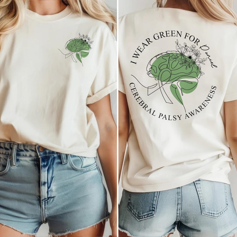 May include: Cream-colored t-shirt with a green brain graphic and the text "I Wear Green for Daniel Cerebral Palsy Awareness." The front of the shirt features a smaller brain graphic. The design includes floral accents.