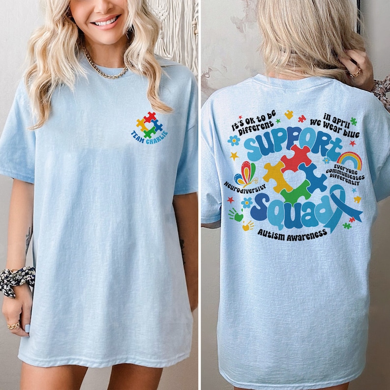 May include: Light blue t-shirt with a puzzle piece design that says "Support Squad" and "Autism Awareness". The back of the shirt has a puzzle piece design with the text "It's ok to be different" and "In April we wear blue".