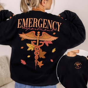 May include: Black sweatshirt with a graphic of a medical caduceus with autumn leaves and the text "EMERGENCY department" on the back. The front of the sweatshirt has a smaller graphic of the caduceus with the text "EMERGENCY DEPT. ELEANOR, IN"