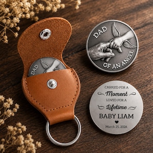 May include: A collection of memorial coins, one inside a brown leather keychain case. The coins are silver-colored, with the words "DAD" and "OF AN ANGEL" engraved on one, and "CARRIED FOR A MOMENT LOVED FOR A LIFETIME BABY LIAM March 25, 2026" on another.