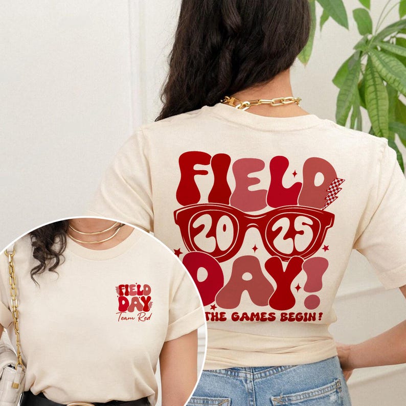 May include: A cream colored t-shirt with a red graphic on the back that says "FIELD 20 25 DAY! THE GAMES BEGIN!" and a smaller red graphic on the front that says "FIELD DAY Team Red".