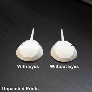 May include: Two 3D printed horseshoe crab models, one with eyes and one without eyes. Both models are white and unpainted. The models are on a black surface.  Unpainted Prints.