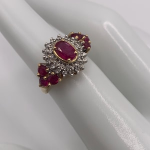 May include: A gold ring with a large oval ruby surrounded by smaller rubies and diamonds.
