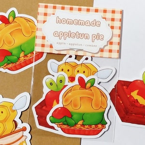 May include: Five stickers featuring a cartoon apple character in various poses. The stickers are themed around apple pie and include a bee, a jar of honey, and a basket of apples. The text on the sticker reads "homemade appletun pie applin - appletun - comber".