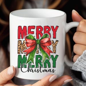 May include: White ceramic mug with the words "MERRY MERRY CHRISTMAS" in red and green, with a leopard print background. A red and green bow is in the center of the mug.