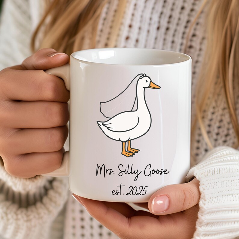 Puede incluir: Taza de cer&aacute;mica blanca con una ilustraci&oacute;n de dibujos animados de un ganso con velo. El texto en la taza dice "Mrs. Silly Goose est. 2025".