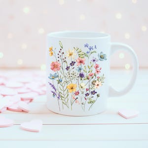 May include: White ceramic mug with a floral design featuring a variety of colorful flowers, including pink, yellow, blue, and purple.