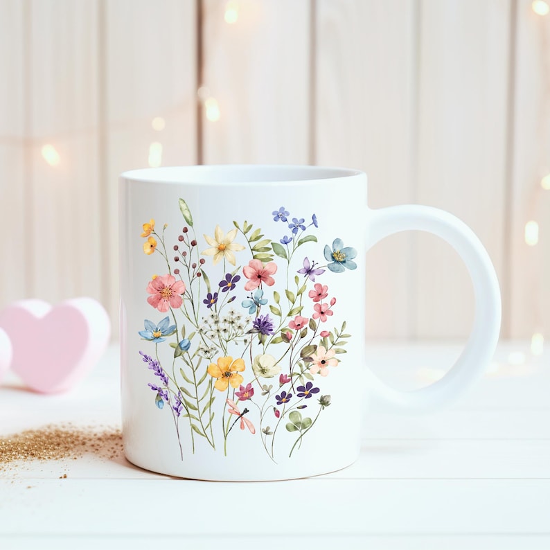 May include: White ceramic mug with a colorful floral design featuring pink, blue, yellow, and green flowers. The mug has a white handle.