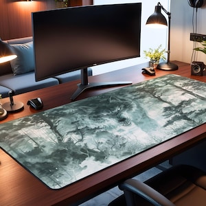 May include: A large gray and white wolf head graphic printed on a rectangular desk mat. The mat is on a wooden desk with a computer monitor and a lamp.