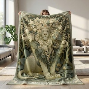 May include: A decorative blanket featuring a detailed illustration of a lion with a floral mane and leafy accents. The color palette includes shades of green, cream, and beige, creating a nature-inspired design. The blanket has a decorative border.