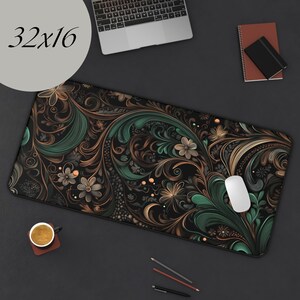 May include: A black and green floral patterned mouse pad with a 32x16 inch size. The mouse pad is on a black surface with a laptop, a cup of coffee, and pencils.
