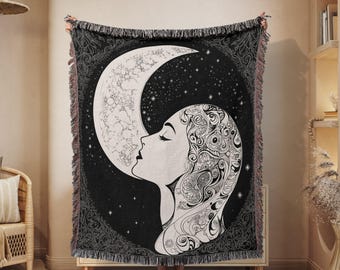 May include: Black and white woven tapestry featuring a woman's face with intricate floral details, looking up at a crescent moon with stars in the background.