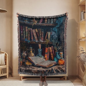 May include: A woven tapestry throw blanket with a dark background featuring a bookshelf filled with antique books, potion bottles, and a vintage book open on a table. The scene is set in a magical, mystical setting.