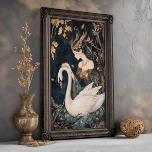 May include: A framed art print featuring a woman with a crown of leaves and a white swan. The woman is wearing a flowing green dress and the swan is resting on her lap. The background is a dark forest with gold leaf accents.