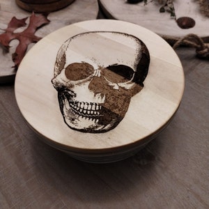 Recipiente de vidrio con tapa de madera grabada con calavera