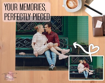 May include: A completed jigsaw puzzle featuring a couple sitting on a bench, with the text "YOUR MEMORIES, PERFECTLY PIECED." The puzzle is on a wooden surface, with a coffee cup and other items nearby. A smaller image of the puzzle is also present.