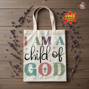 May include: Cream-colored tote bag with the text "I AM A child of GOD" in various colors. The bag has a cross symbol within the word "GOD". The background is a wooden surface with lavender sprigs.