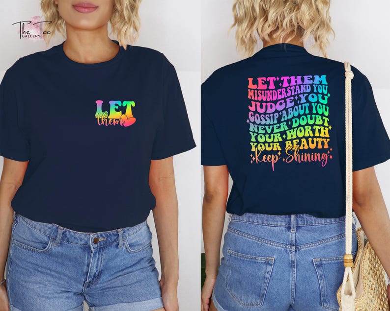 May include: A navy blue t-shirt with a rainbow gradient design that says "Let them" on the front and "Let them misunderstand you, judge you, gossip about you, never doubt your worth, your beauty. Keep shining." on the back.