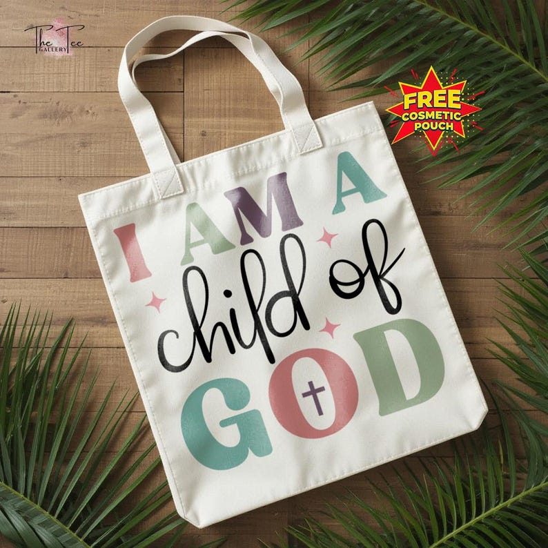 May include: A white tote bag with the text "I AM A child of GOD" in various colors. The bag has a simple design with a cross symbol in the word "GOD". The bag has two white handles.