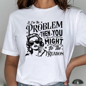 Peut inclure: T-shirt blanc avec un motif noir. Il présente une femme vintage portant des lunettes de soleil et tenant un verre, avec le texte : « Si je suis le PROBLÈME, alors VOUS pourriez être la RAISON ».