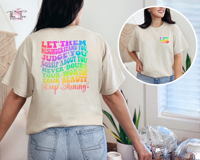 May include: A beige t-shirt with a rainbow-colored graphic on the back that says "Let them misunderstand you, judge you, gossip about you, never doubt your worth, your beauty, Keep Shining."