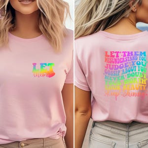 May include: Pink t-shirt with a rainbow graphic that says "Let them" on the front and "Let them misunderstand you, judge you, gossip about you, never doubt your worth, your beauty, keep shining." on the back.