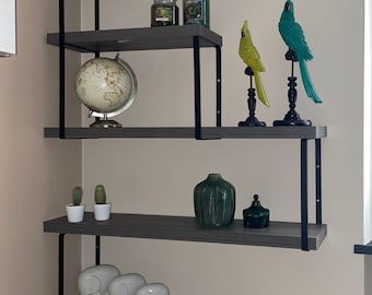 May include: A gray and black corner shelf unit with various decorative items. The shelves display a white skull, candles, bird figurines, a globe, cacti, vases, elephant figurines, books, and a rose arrangement.